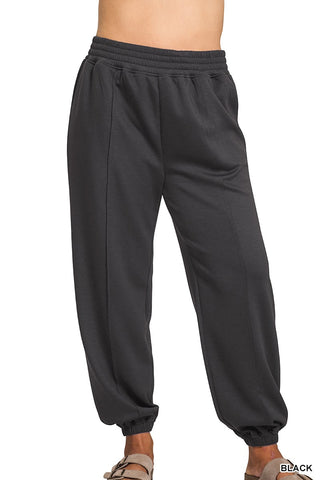 Black sweatpants worn by a person on a white background