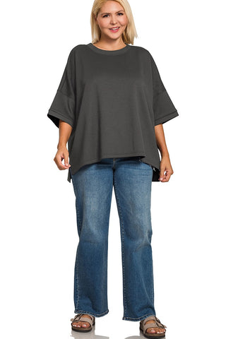 Woman wearing a gray oversized top and blue jeans on a white background