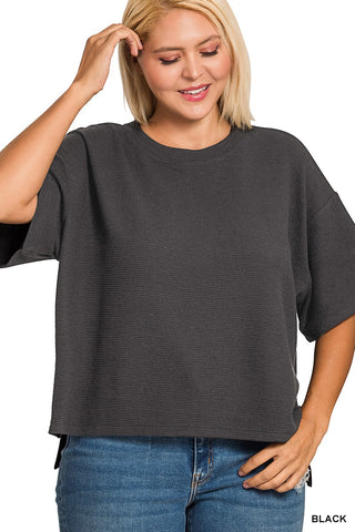 Woman wearing a dark gray oversized t-shirt and blue jeans on a white background