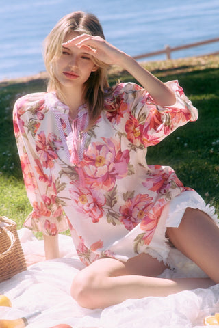 Woman in a floral dress sitting on grass by a body of water