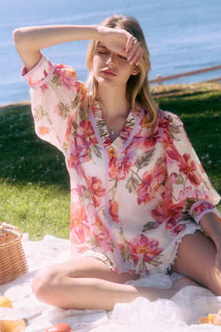 Woman in a floral dress sitting on a blanket by the water