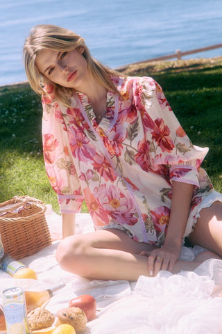 Woman in a floral dress sitting on a picnic blanket by the water