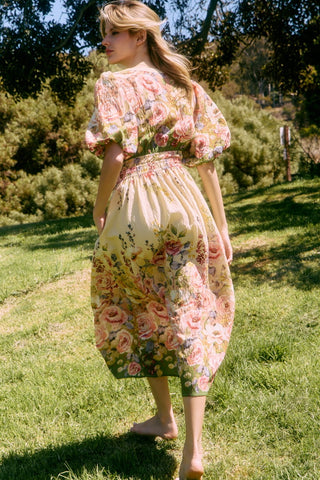 Woman in a floral dress standing in a grassy outdoor setting