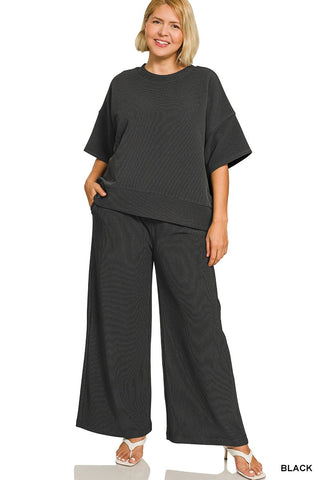 Woman wearing a black outfit with wide-leg pants on a white background