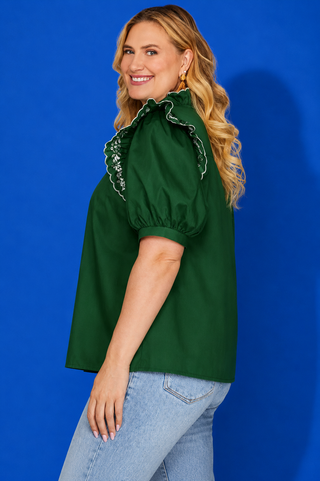 Green puff-sleeve blouse with light-wash jeans.