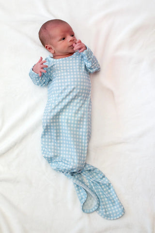Newborn baby wrapped in a blue checkered swaddle on a white background