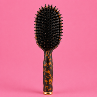 Hairbrush with tortoiseshell handle on a pink background