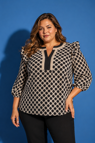 Woman wearing a polka dot blouse against a blue background