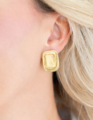 Gold earring worn by a person with blonde hair.