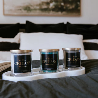 Three candles labeled 'Orleans' on a marble tray with a blurred indoor setting.
