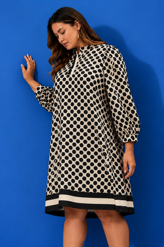 Woman wearing a polka dot dress against a blue background