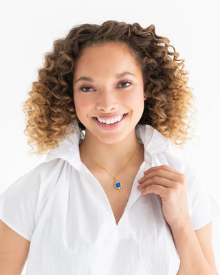 Woman wearing a white shirt and a necklace with a blue pendant on a white background