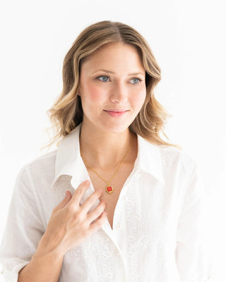 Woman wearing a white shirt and a necklace with a red pendant on a white background