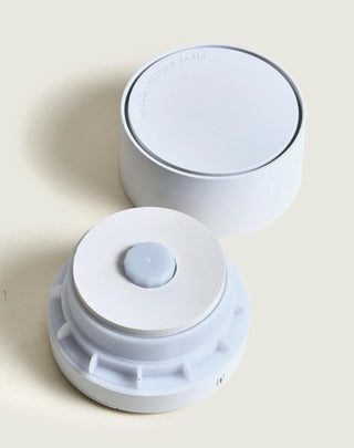 Two white cylindrical objects with circular tops on a light beige background