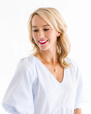 Woman wearing a light blue blouse with a plain white background