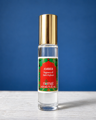 Nemat Amber fragrance oil roll-on in a clear glass bottle with a decorative red and green label and gold cap.