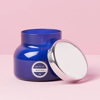 Blue candle jar with a white lid on a pink background