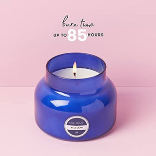 Blue candle with a label on a pink background, showing 'burn time up to 85 hours'.
