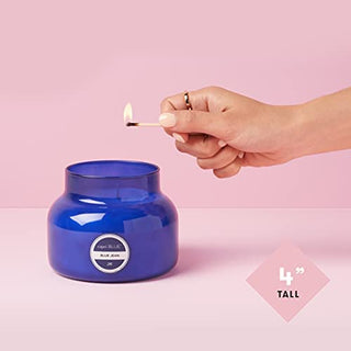 Hand lighting a blue candle with a pink background