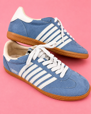 Blue sneakers with white stripes on a pink background