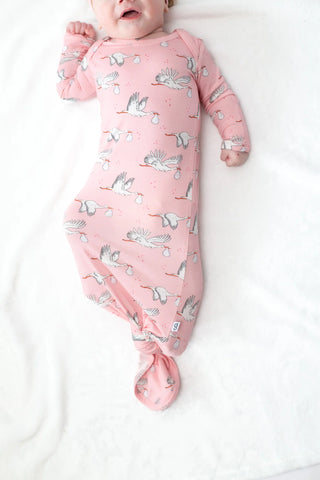 Baby wrapped in a pink blanket with stork design on a white background