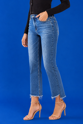 A model wearing medium-wash blue cropped flare jeans with a raw frayed hem
