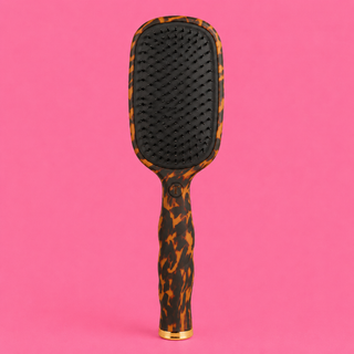Hairbrush with a tortoiseshell pattern on a pink background