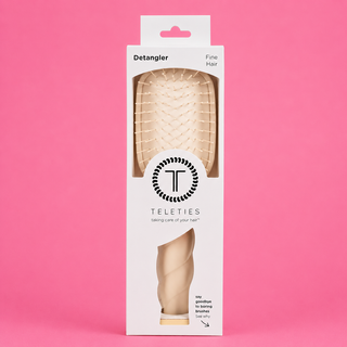 Packaged hair detangler brush with 'Teleties' branding on a pink background