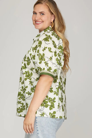 Woman wearing a green floral patterned shirt against a plain background