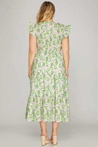 Woman wearing a green leaf-patterned dress on a plain background