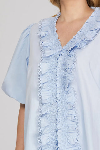 Light blue ruffled blouse with a plain background