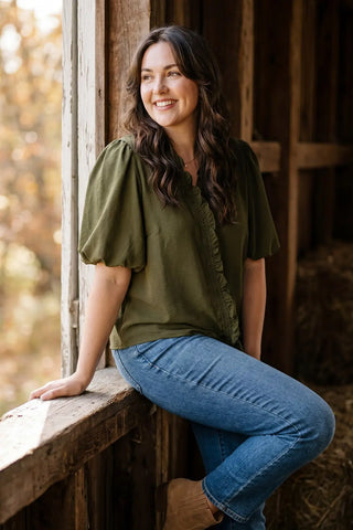 Woman sitting on a wooden ledge with a blurred natural background