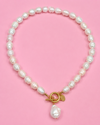 Pearl necklace with a gold clasp on a pink background