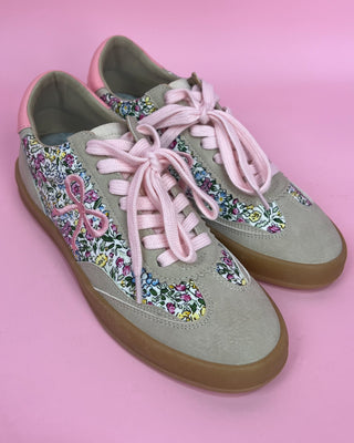 Floral-patterned sneakers with pink laces on a pink background