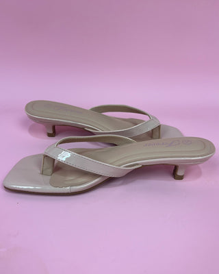 Beige high-heeled sandals on a pink background