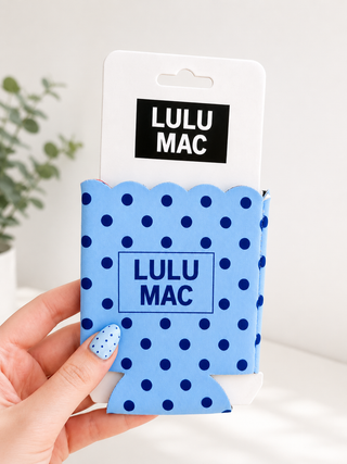 Blue polka dot can cooler with Lulu Mac branding held by a hand.