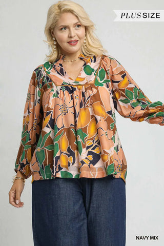 Woman wearing a plus-size floral blouse with navy pants on a white background