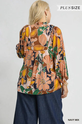 Woman wearing a plus-size floral blouse with navy pants on a white background