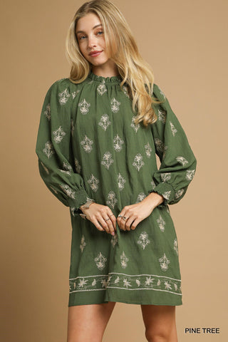 Woman wearing a green dress with floral patterns on a beige background