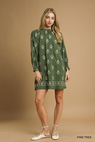 Woman wearing a green patterned dress against a beige background