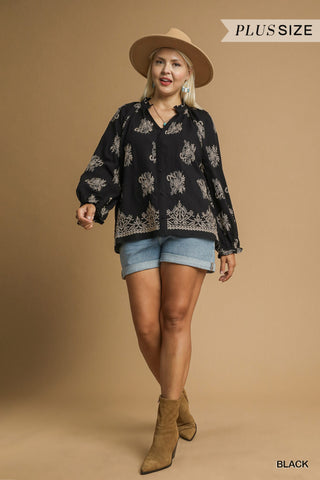 Woman wearing a black patterned blouse, denim shorts, and brown boots on a beige background