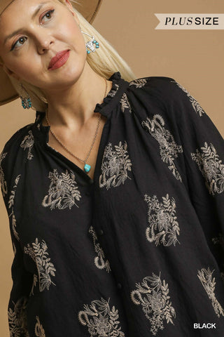 Woman wearing a black blouse with white embroidery on a beige background