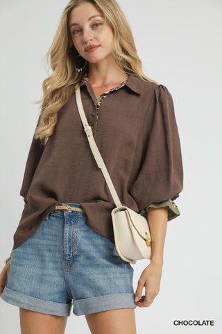 Woman wearing a brown shirt and blue shorts with a beige crossbody bag on a white background