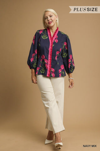 Woman wearing a navy floral blouse with pink accents on a beige background