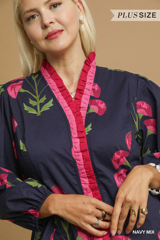 Woman wearing a navy dress with pink floral embroidery on a beige background