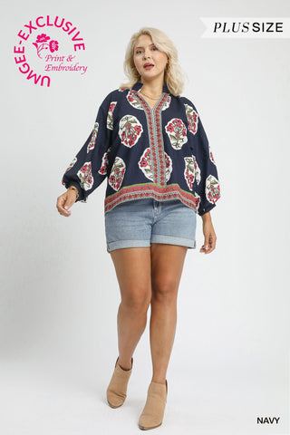 Woman wearing a navy blue floral blouse with denim shorts on a white background, featuring Umgee Exclusive branding.
