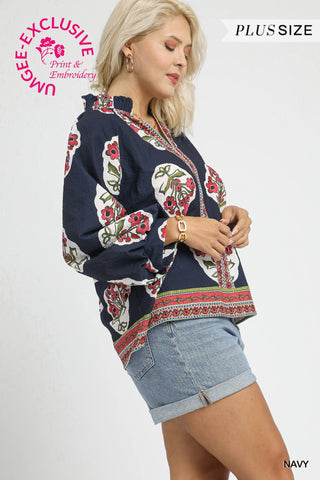 Woman wearing a navy blue embroidered top with floral patterns on a white background