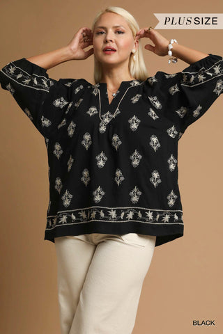 Woman wearing a black blouse with white patterns on a brown background