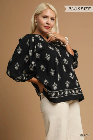 Woman wearing a black blouse with white patterns on a beige background