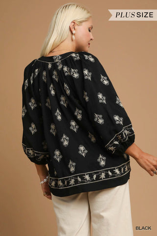 Woman wearing a black blouse with white patterns on a beige background